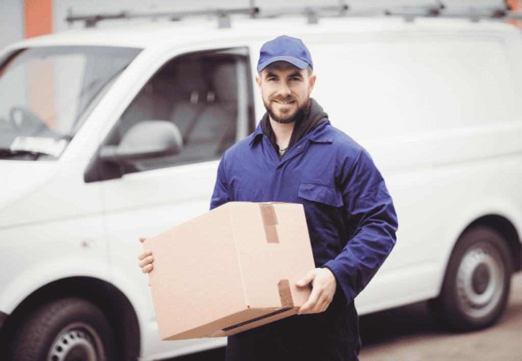 Delivery driver holding a parcel next to his van